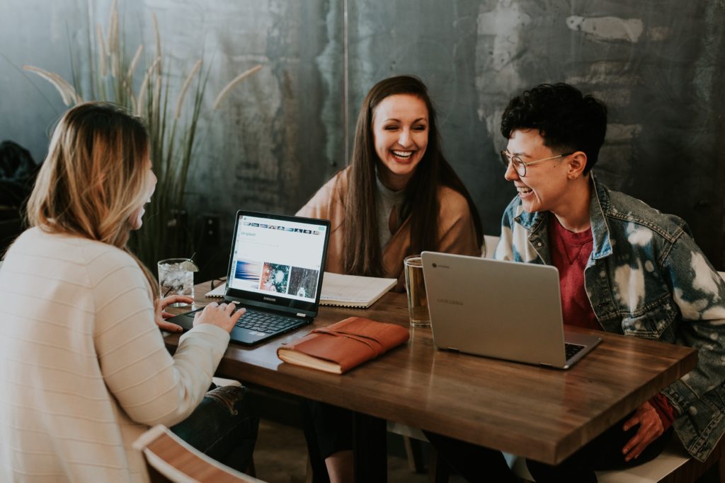 three-people-sitting-around-a-table-laughing-and-working