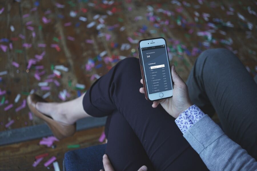 powerpoint presentation quiz questions with answers Person holding iPhone displaying Competitions leaderboard, with confetti on the floor