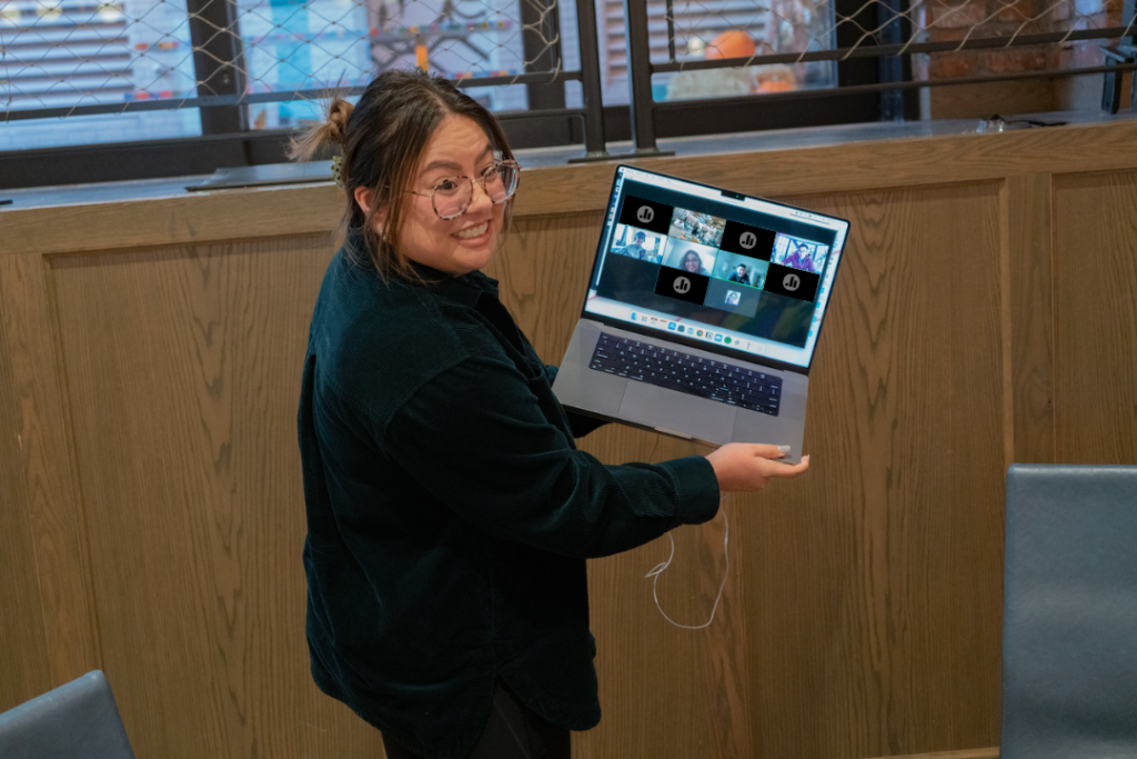 female presenting individual holding up a laptop