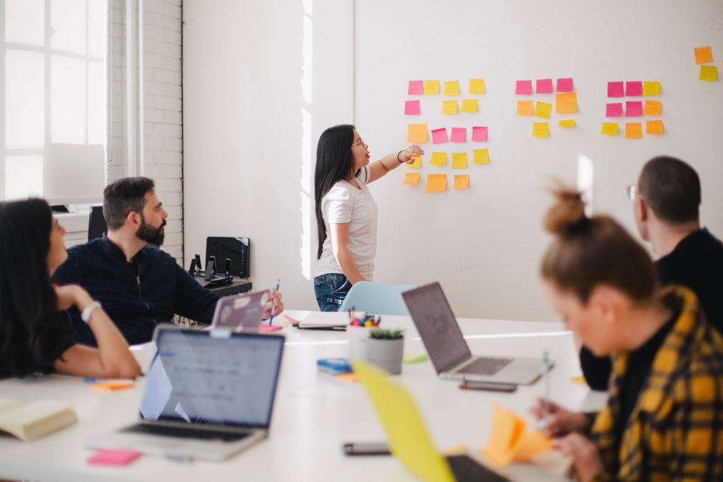 group-of-people-sitting-in-front-of-whiteboard-with-sticky-notes