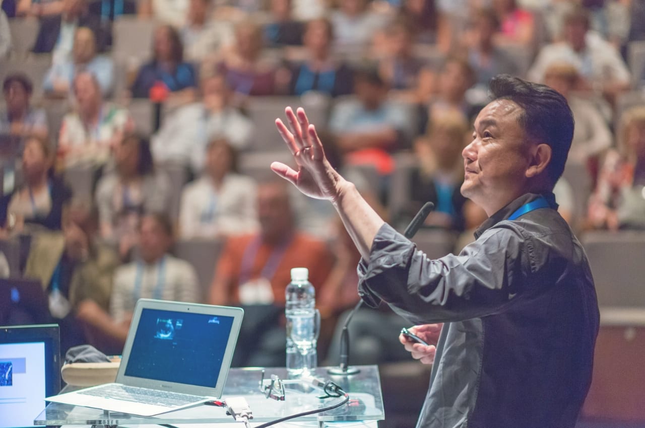 Presenter speaking to a room full of people.